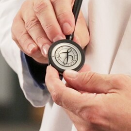 Gros plan d'un médecin tenant le devant d'un stéthoscope 3M Littmann.